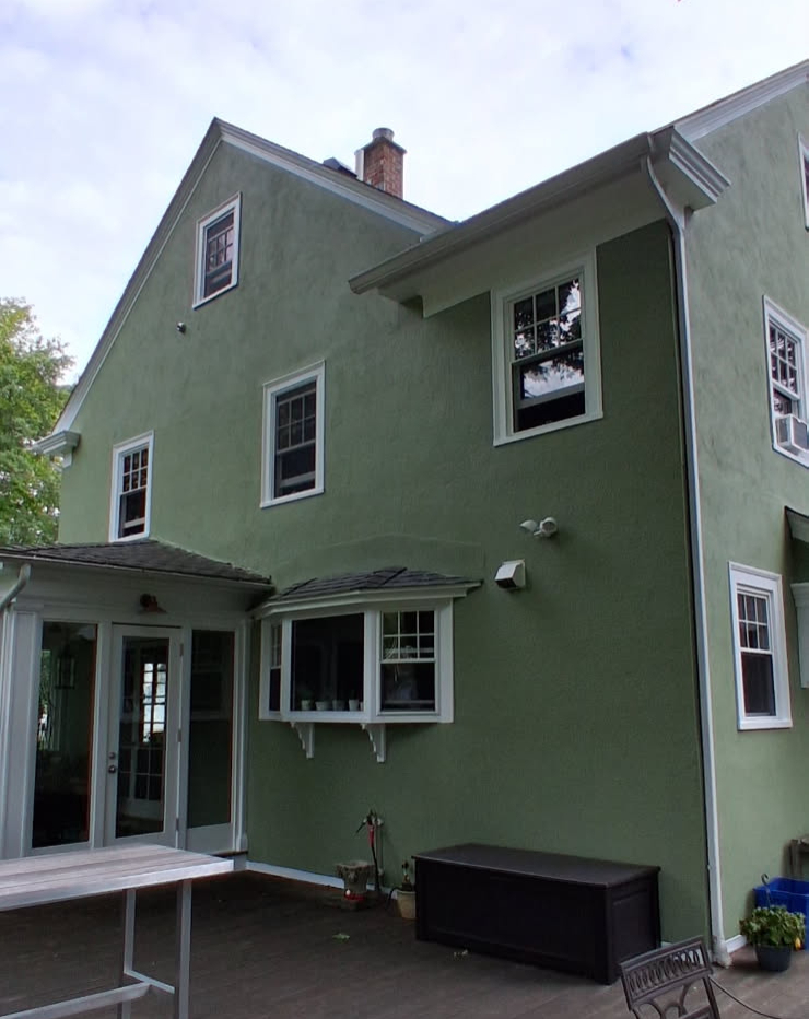 The same stucco colonial finished in sage green with fresh white trim and clean gutter lines