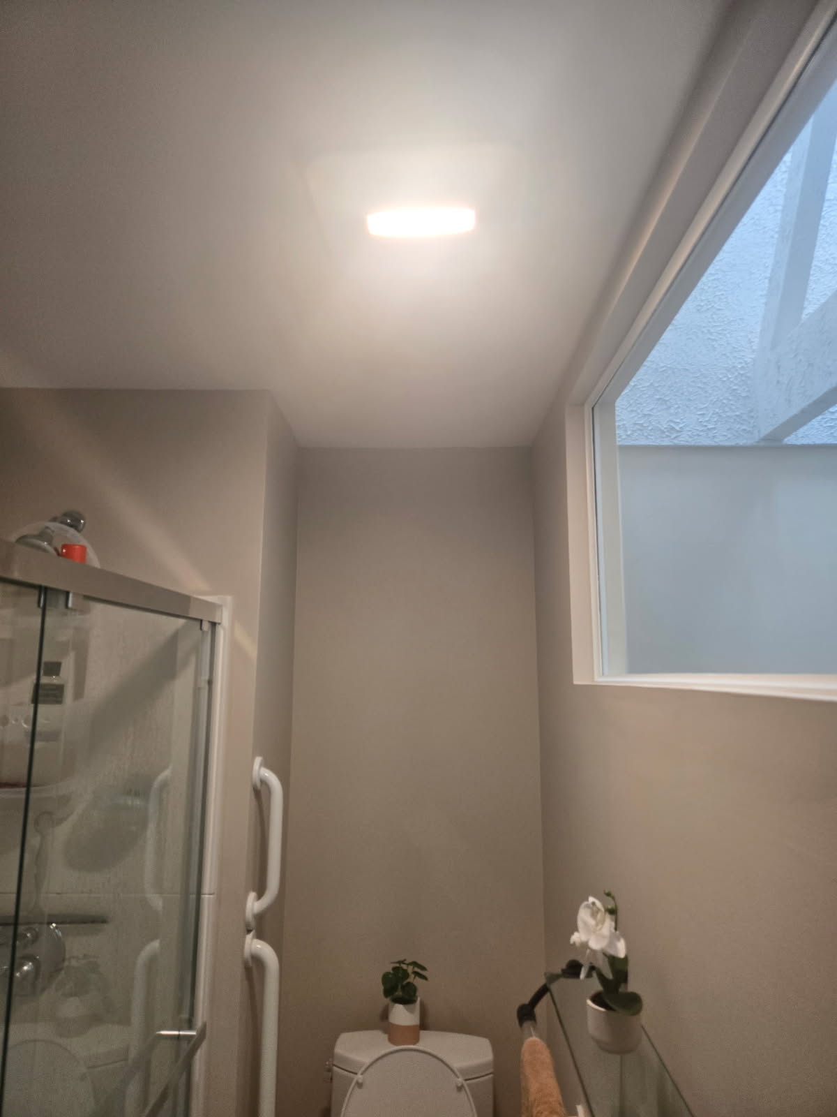 The same bathroom after repainting in smooth warm greige with a clean white ceiling and trim