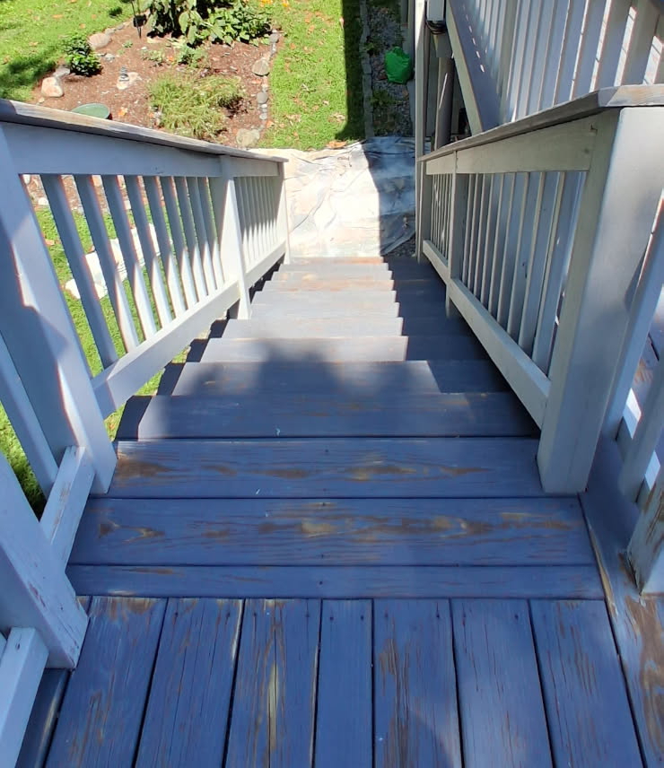 Worn deck stairs and railings with faded blue-grey stain flaking off the treads