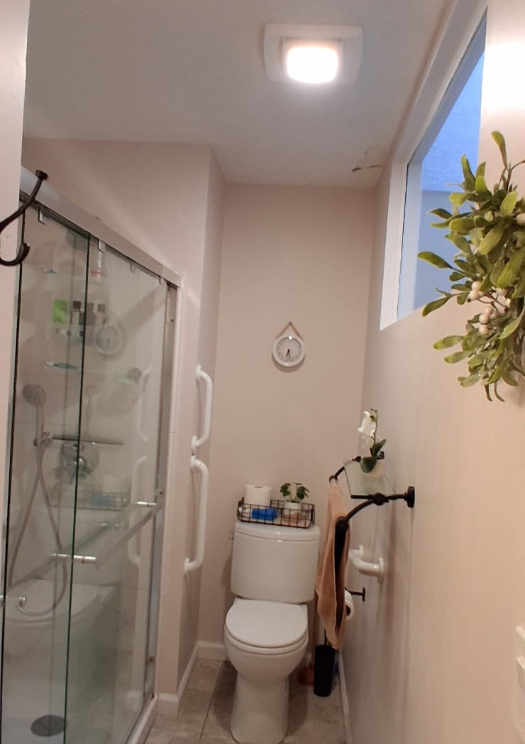 Bathroom before repainting, with scuffed pink-beige walls and a stained ceiling around the fan